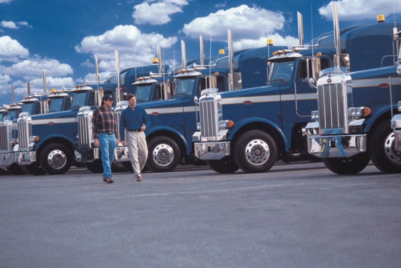 Two men walking in front of a fleet of shiny blue trucks